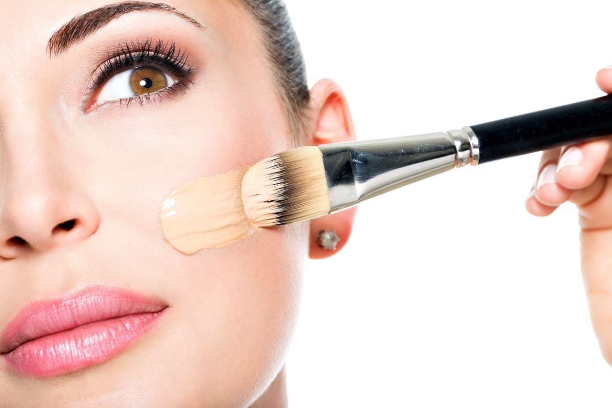 Applying liquid foundation on the face of the woman
